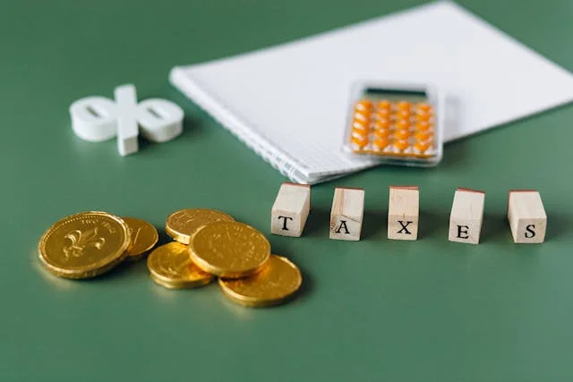 Monedas, dinero, calculadora y un texto que dice Taxes indicando los impuestos